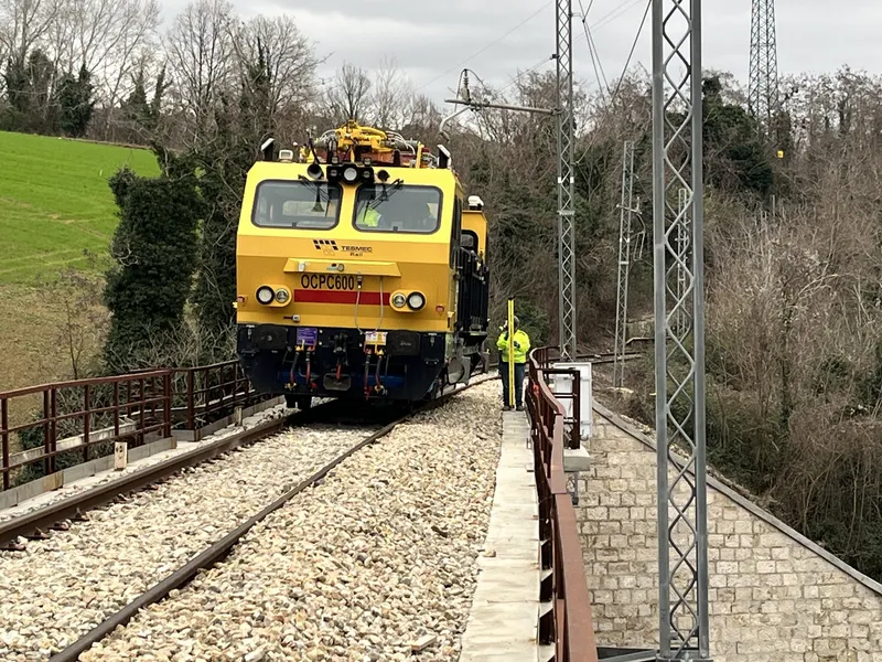 Locomotore di prova fermo su un ponte ferroviario durante un collaudo, con un tecnico a lato del binario