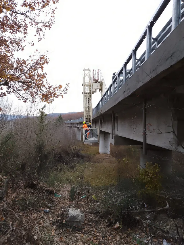 Ispettori su una piattaforma by-bridge sotto l'impalcato di un viadotto